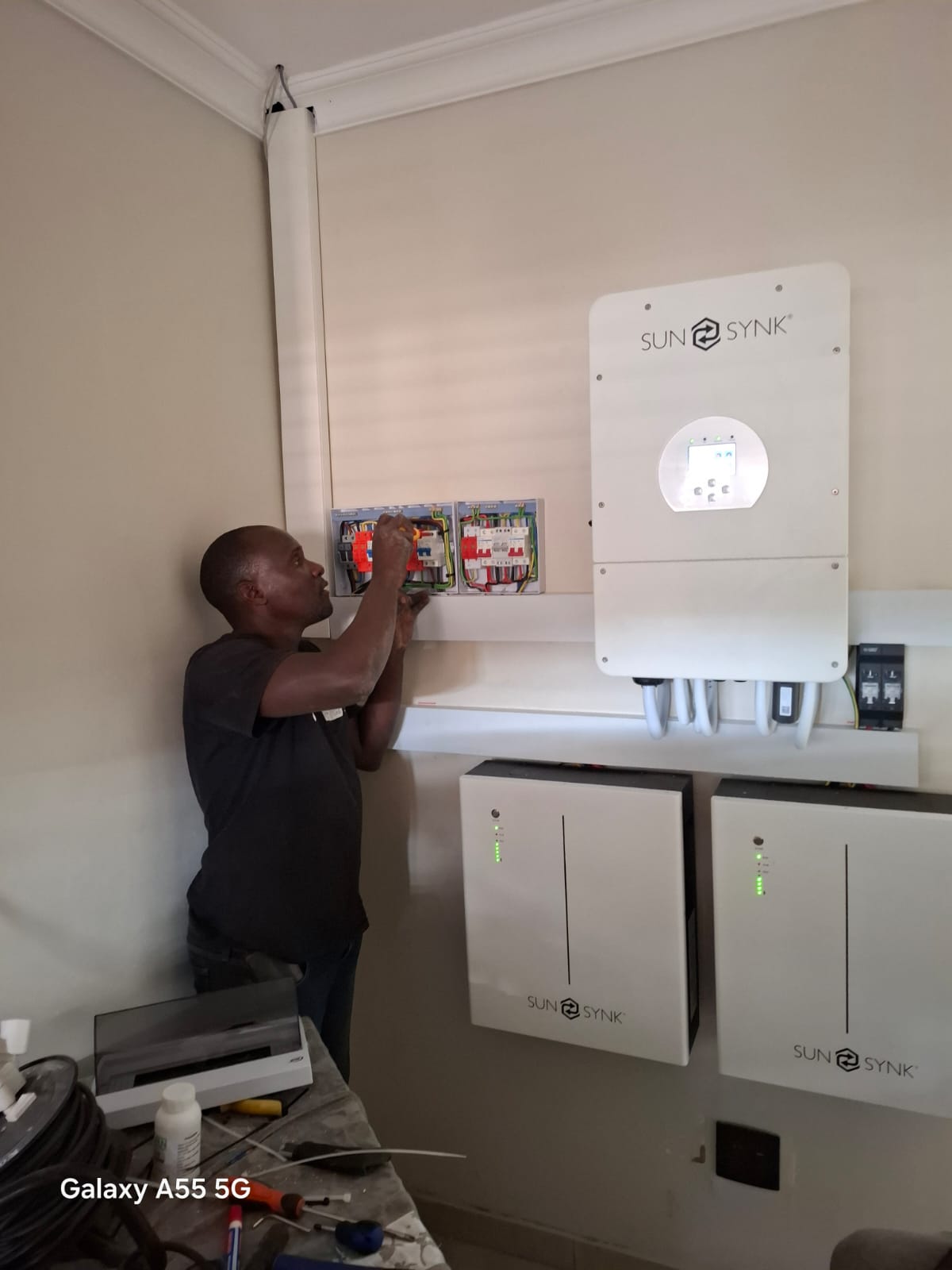 Technician standing beside installed inverter and battery equipment